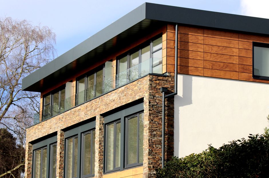 Contemporary house featuring a striking mix of stone and wood facade with large windows.